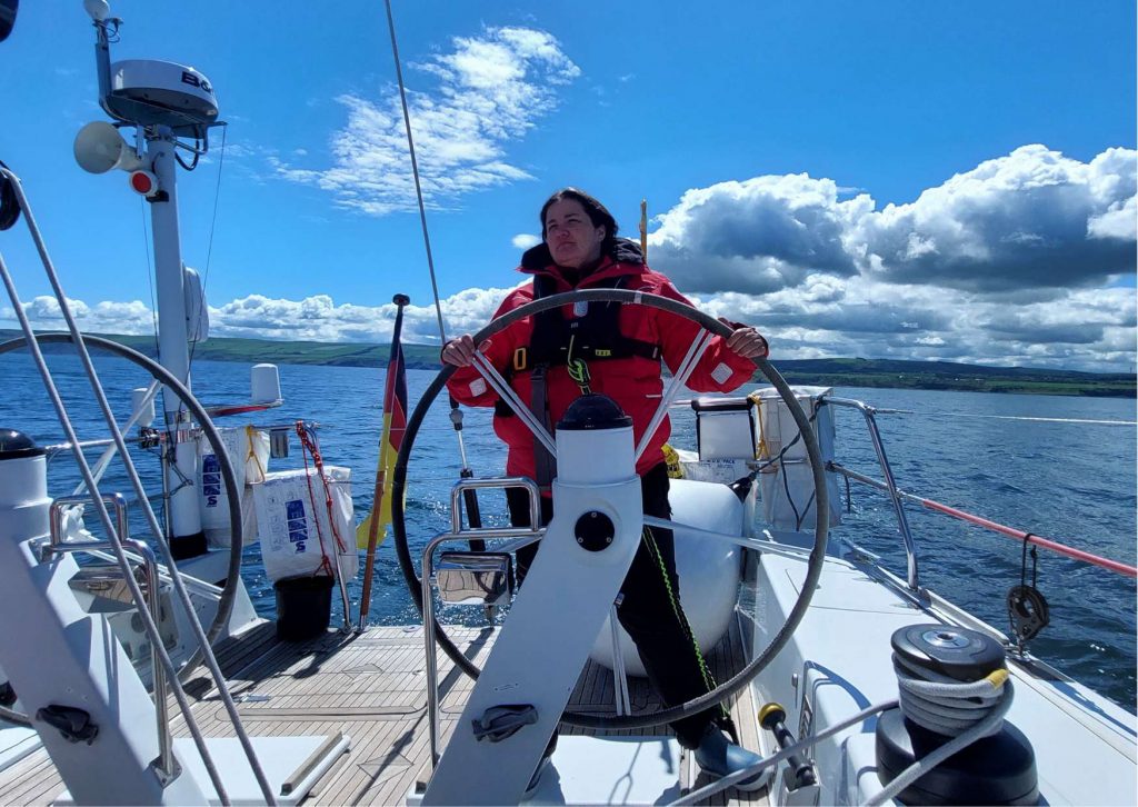 Fun Facts über Antoinette Lühmann, sie steht auf einem Segelboot und steuert das Schiff